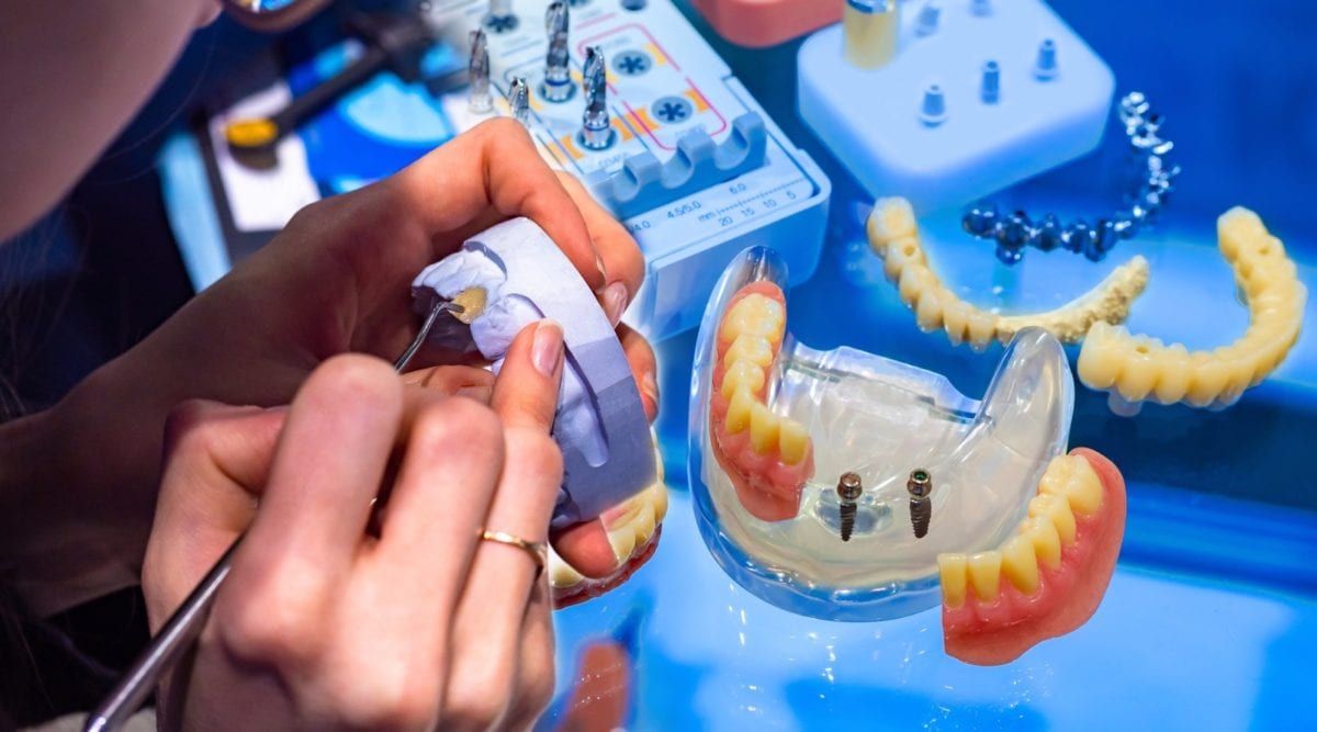 Women working on one of the teeth on partial dentures