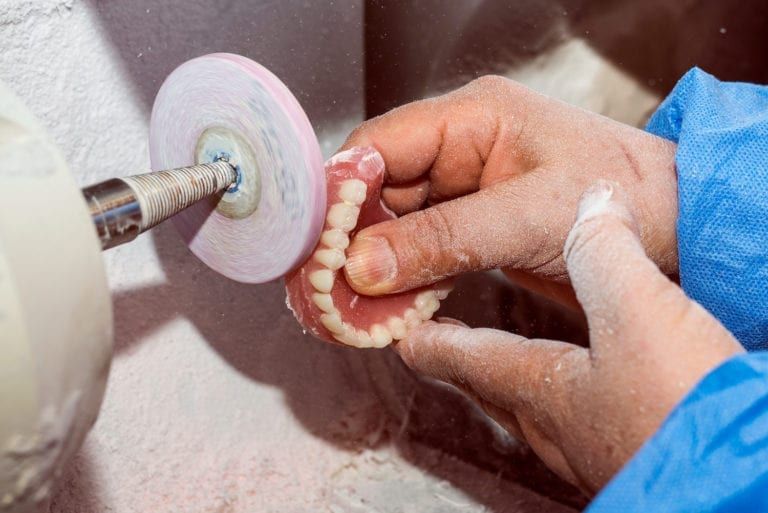 Man sanding off dentures using a machine